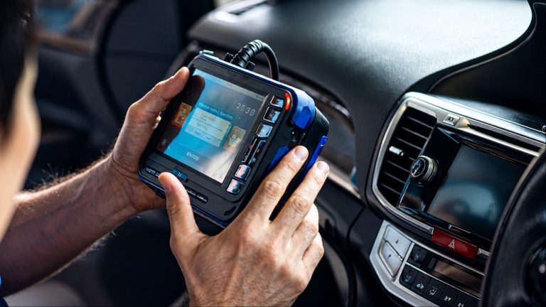 Mechanic using a diagnostic scanner inside a vehicle to identify electronic system faults