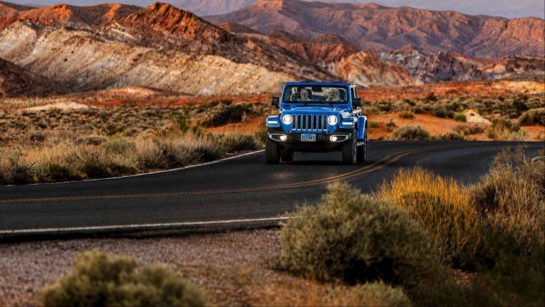 Blue Jeep driving on a winding desert road through mountains