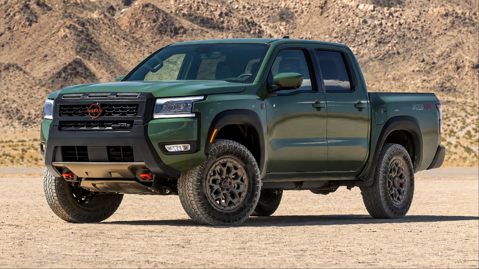 Green Nissan Frontier parked in a sandy desert landscape
