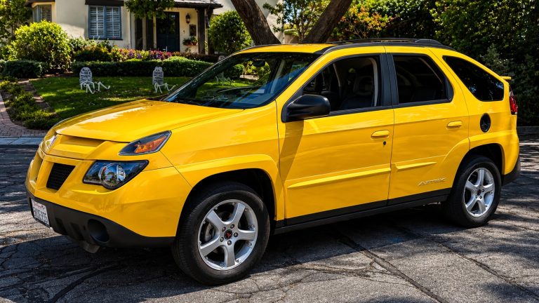 A yellow Pontiac Aztek is standing in a house parking