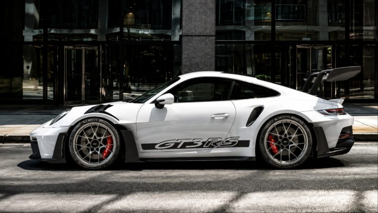 Porsche 911 GT3 RS parked curbside, showcasing its aggressive aerodynamic design and large rear wing