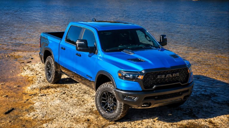 Blue Ram 1500 Rebel pickup truck parked on rocky lakeshore