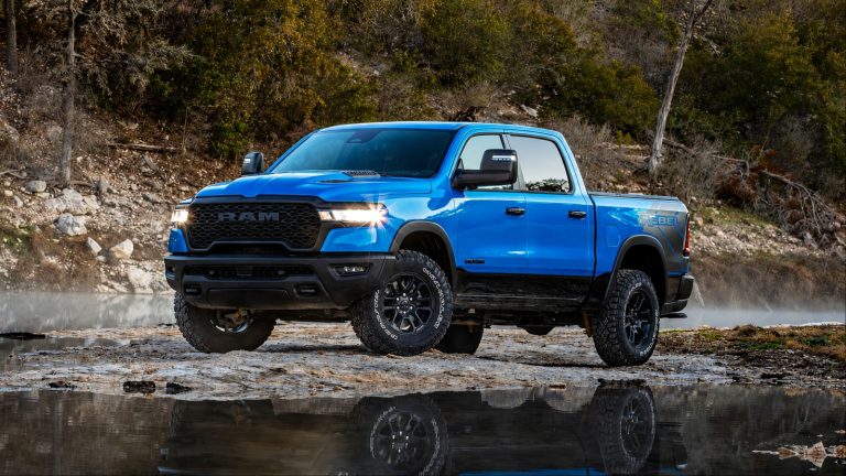 Ram 1500 pickup truck parked on rocky terrain, featuring rugged off-road styling and striking blue paint