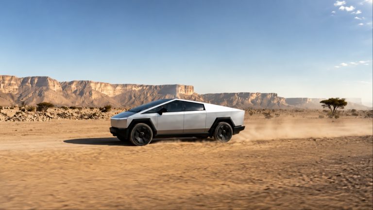 A Tesla Cybertruck drives across a dusty desert plain beneath towering cliffs