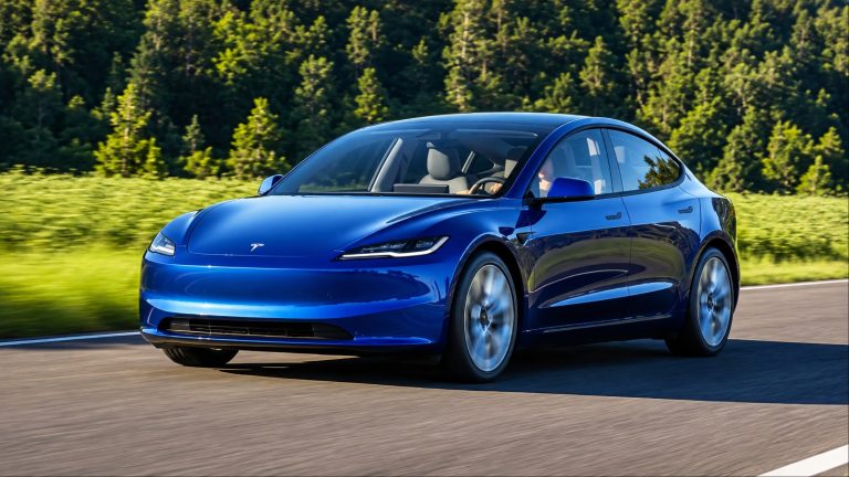 Blue Tesla Model 3 driving along a scenic forest road