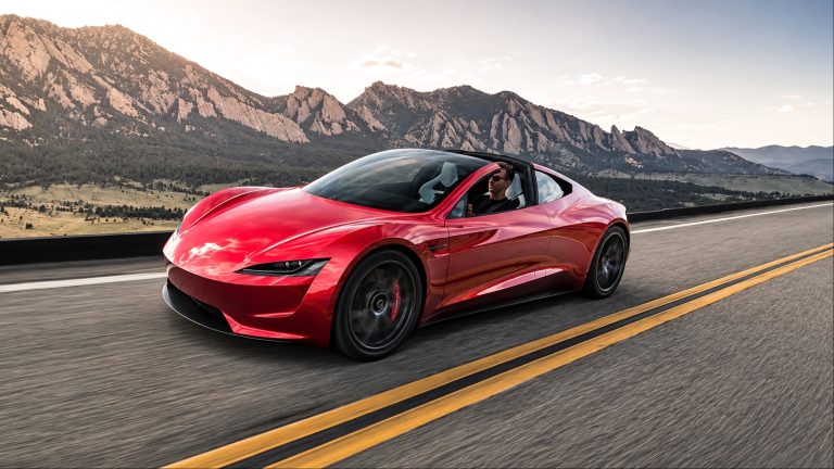 red sports car drives along a scenic mountain highway with a driver inside