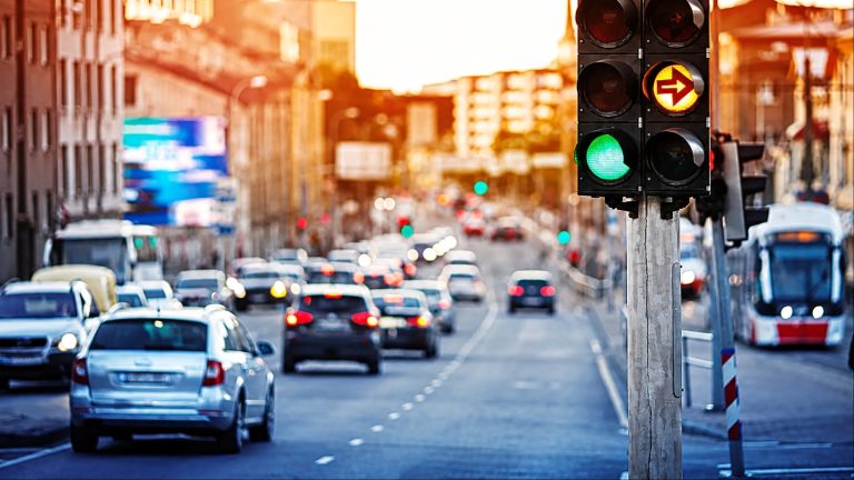busy city street during sunset with cars waiting at a traffic light