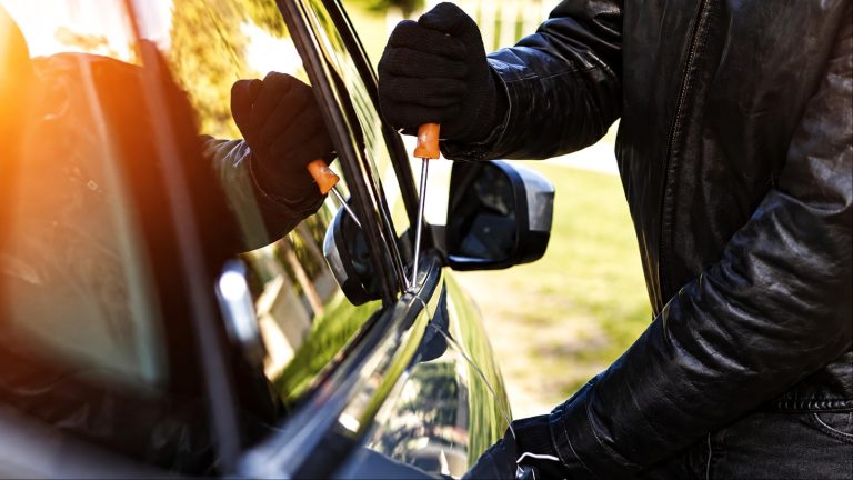 thief is using a screwdriver to break into a carb