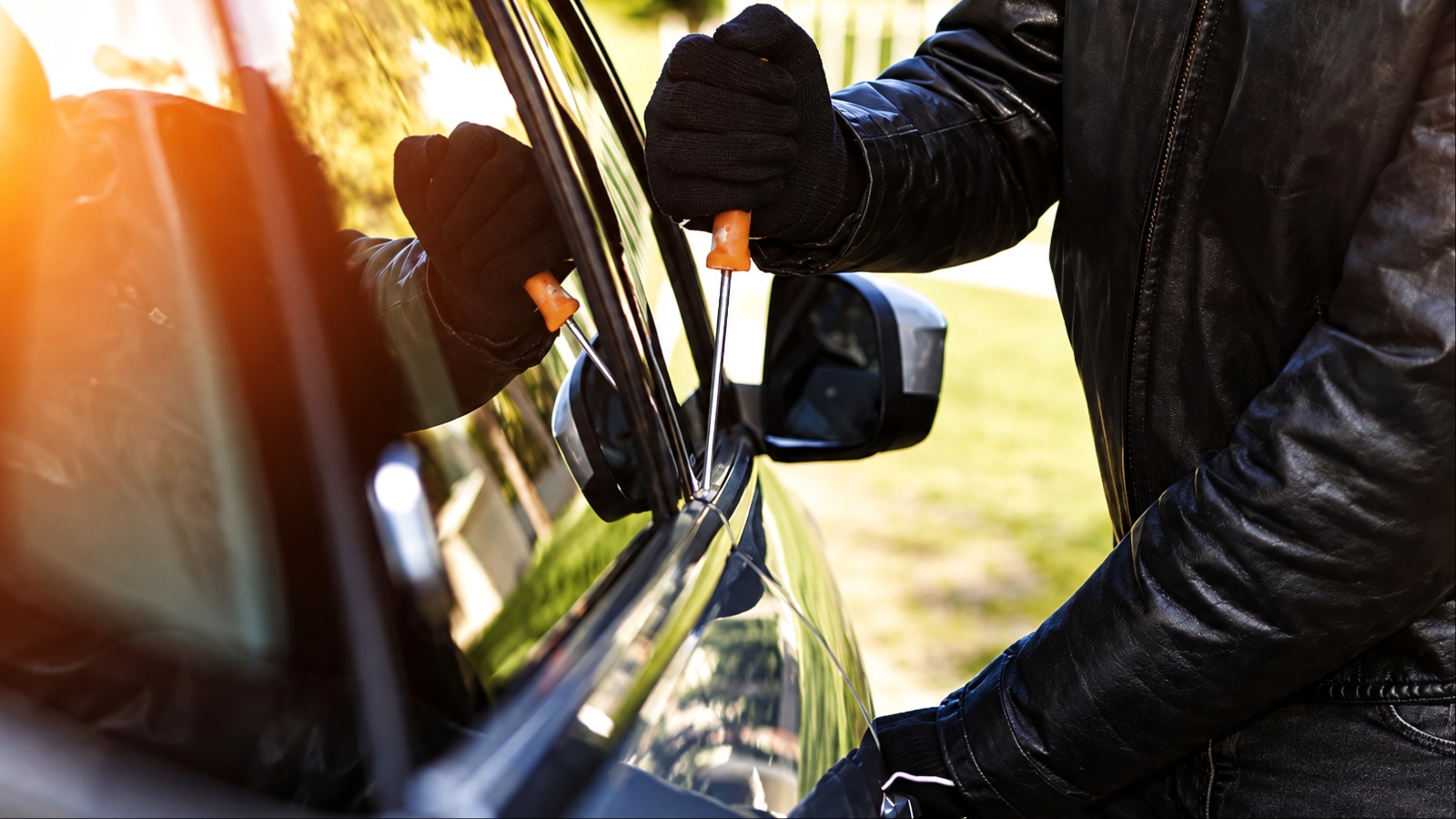 thief is using a screwdriver to break into a carb