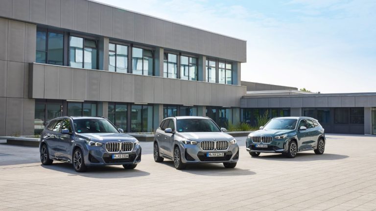 Three BMW SUVs displayed outside a modern building under a clear blue sky