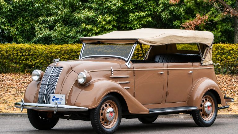 vintage brown Toyoda Model AA car parked outdoors with a tan convertible top