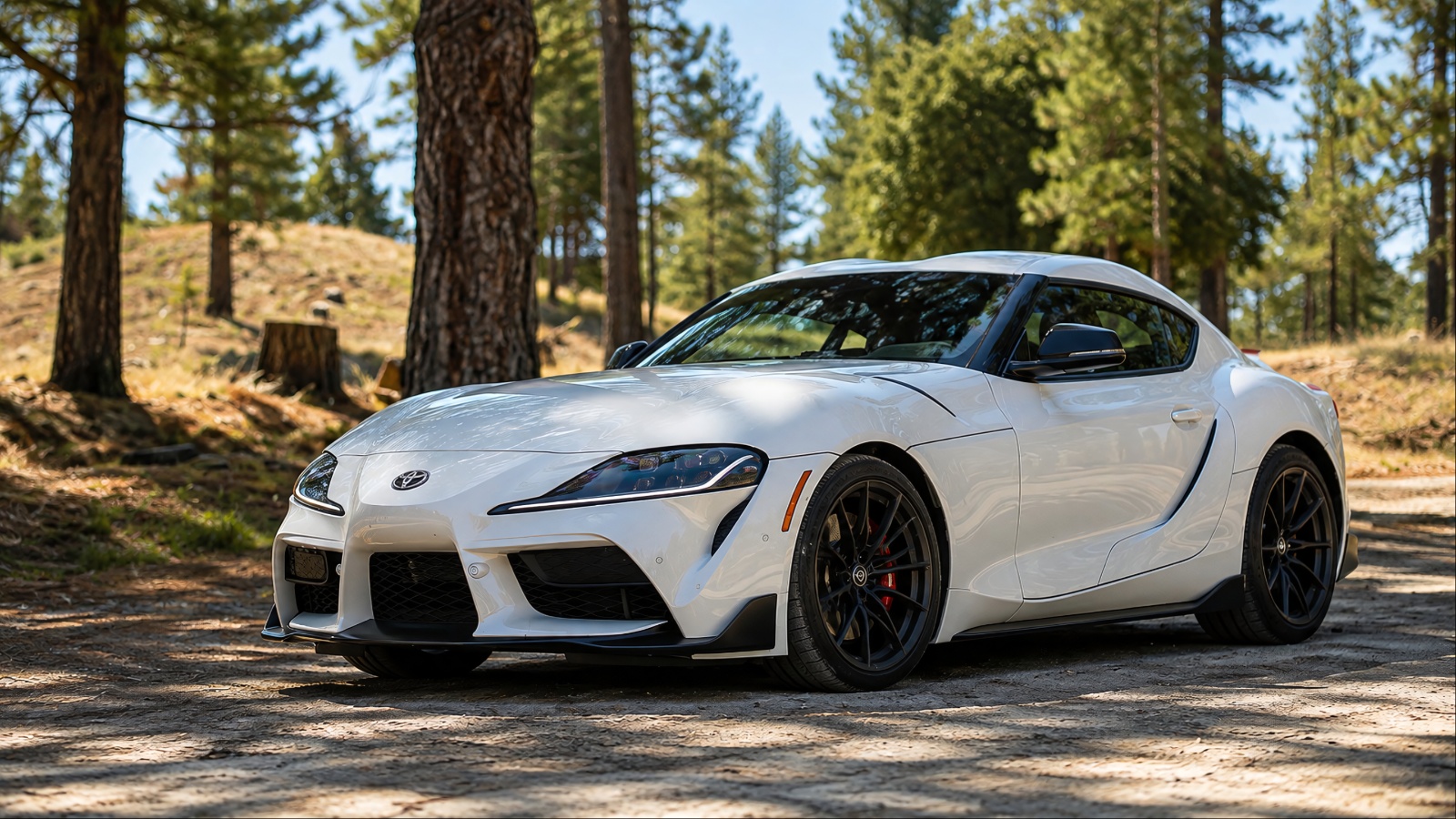White Toyota GR Supra sports car parked on forest dirt road