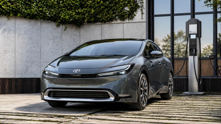 Toyota Prius parked beside a charging station outside a modern building