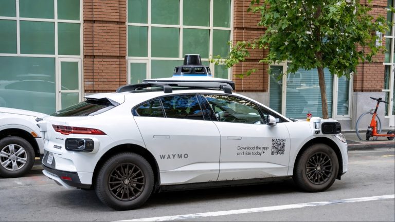 Waymo autonomous vehicle parked on a city street with rooftop sensors