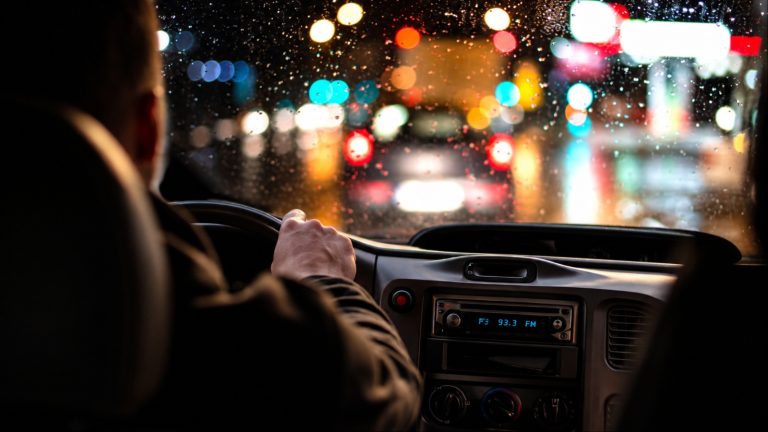 rainy night, blurred city lights, hand on wheel