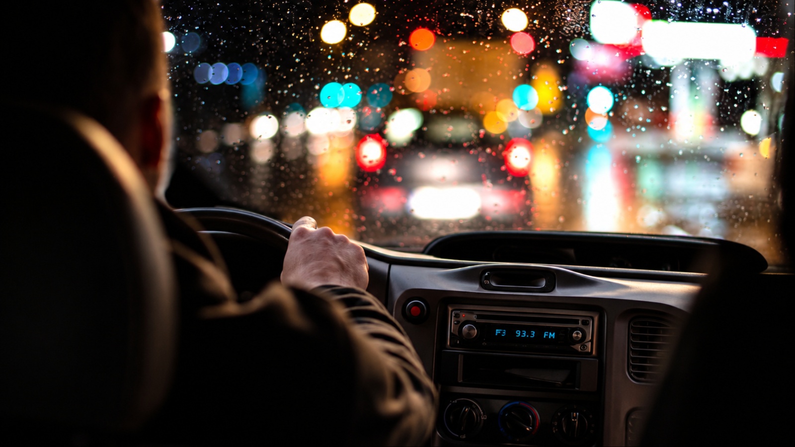 rainy night, blurred city lights, hand on wheel