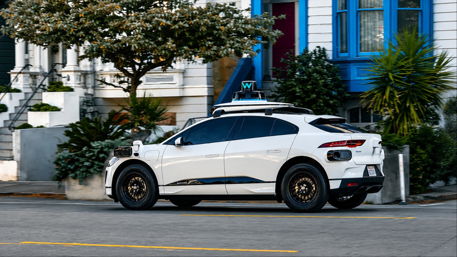 Side view of white Waymo autonomous vehicle on residential street