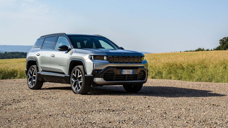A Jeep Compass is standing on the track near a green grass