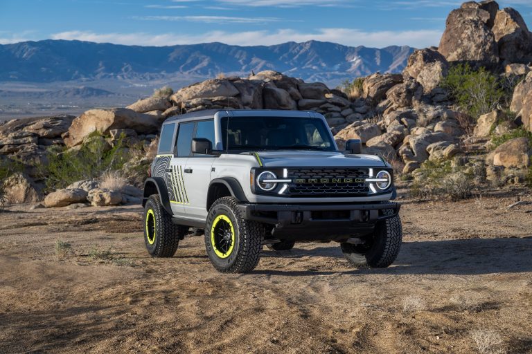 A Ford Bronco is standing on a hilly road on a sunny day