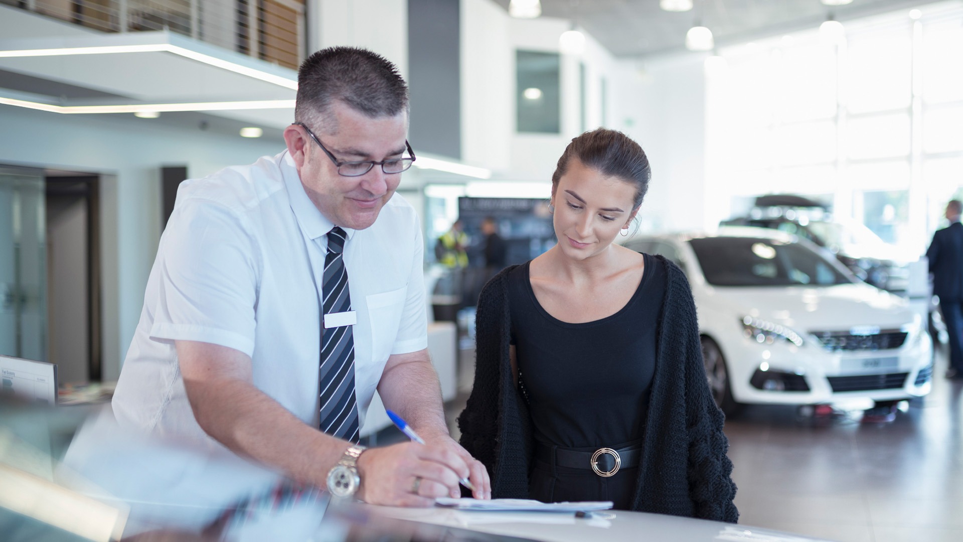 Car salesman signing a document with a customer