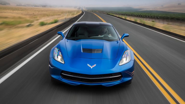 Blue Chevrolet Corvette Stingray speeding on a foggy rural road