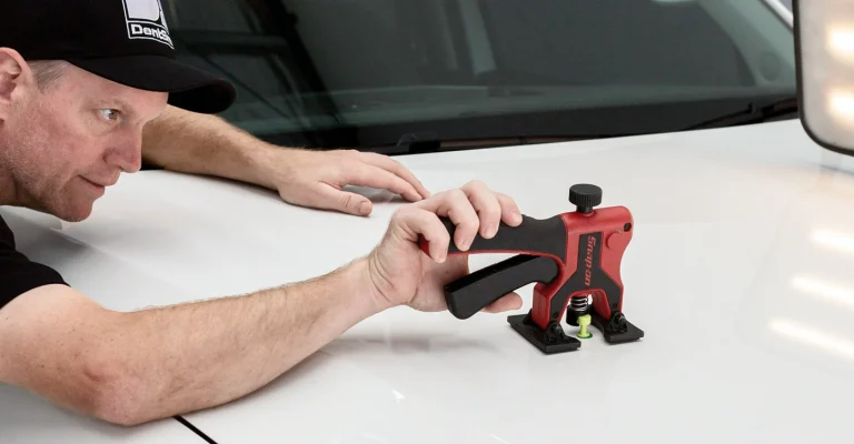 A mechanic is trying to remove the dent with a tool