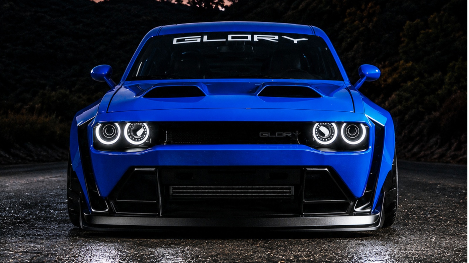 Blue modified Dodge Challenger with Glory branding on wet road