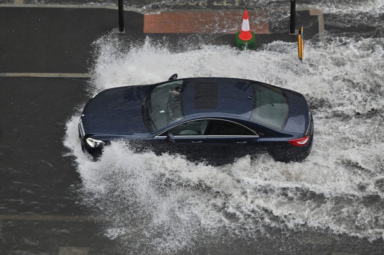 A car is driving through huge water blockage