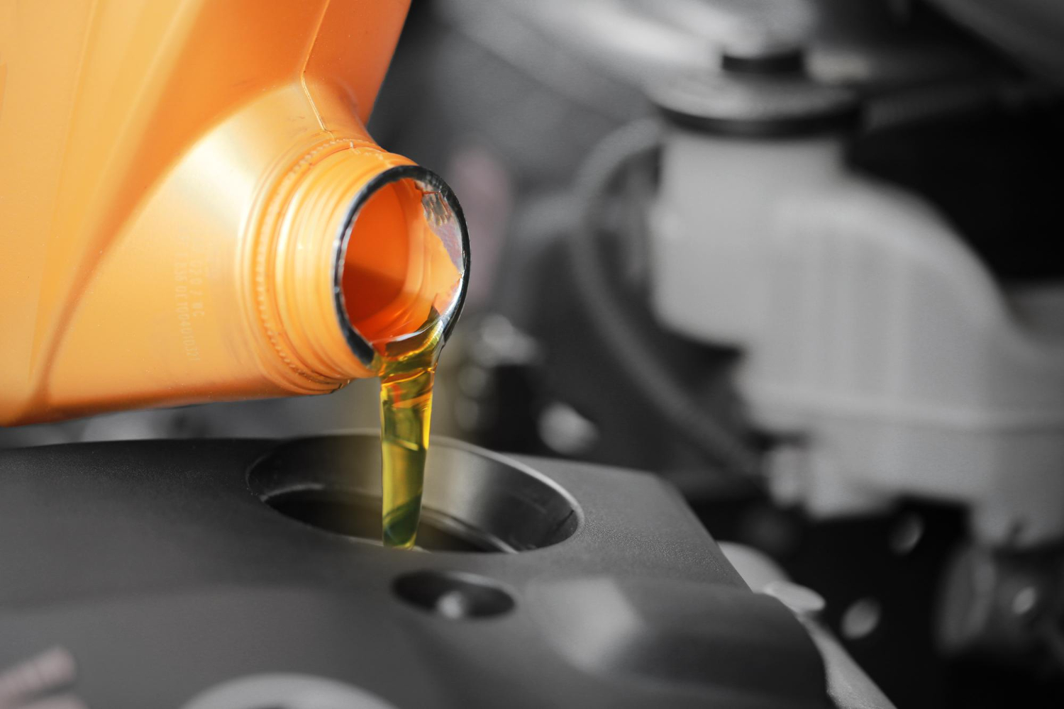 A man is pouring oil in the car's engine