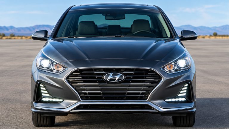 Front view of dark gray Hyundai Sonata with headlights on