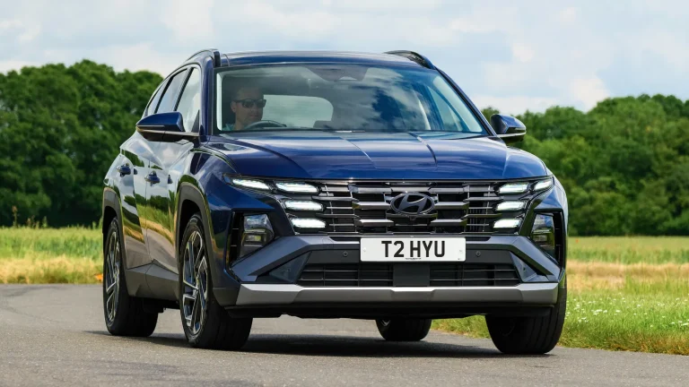 A blue Hyundai Tucson is cruising on a highway
