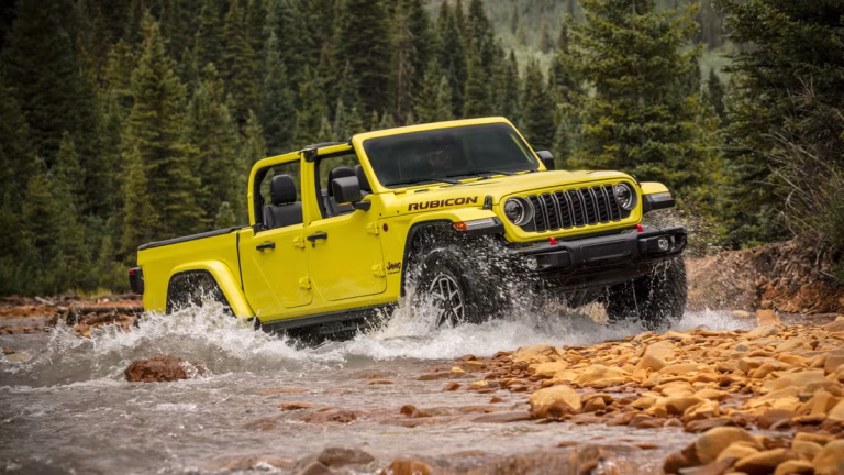 Jeep Gladiator Rubicon splashes through a rocky forest stream