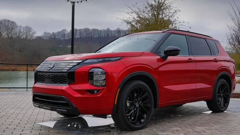 A red Nissan Rogue is standing on a cloudy day