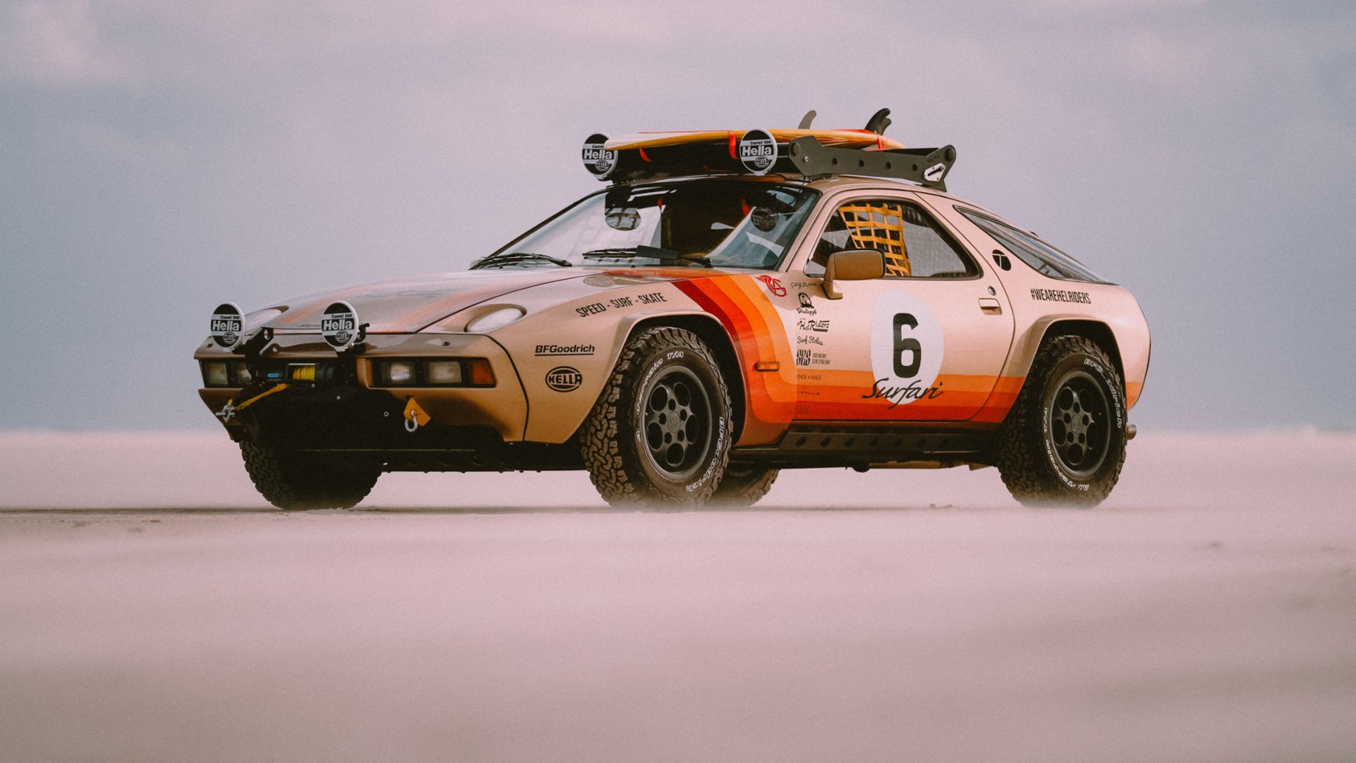 A Porsche in a modified state is cruising on a sandy road