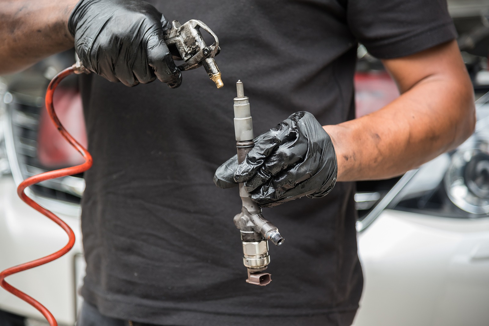 Using an air blow gun to clean a car's fuel injector