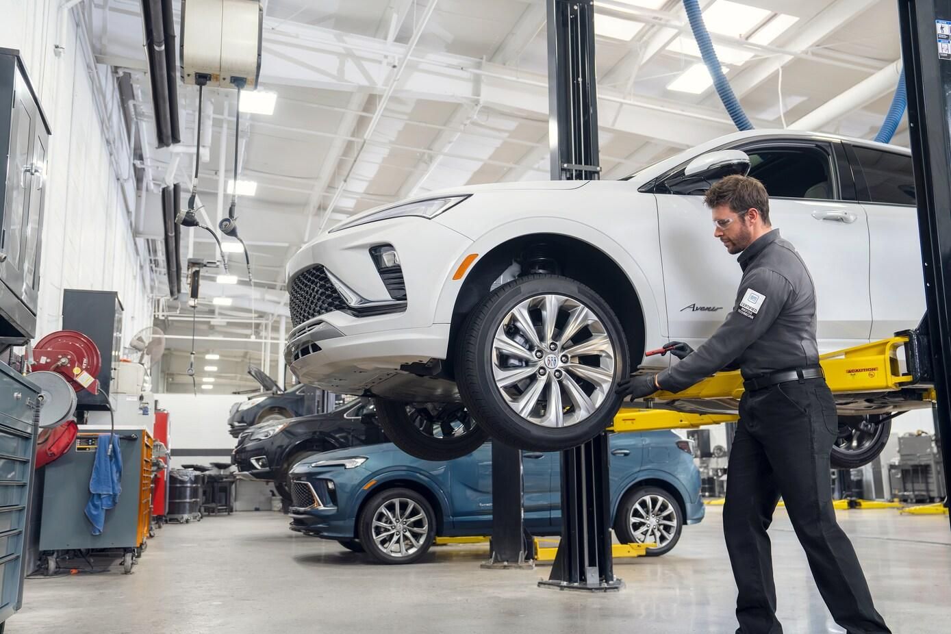 Dealer technician inspecting a vehicle on a service lift during manufacturer warranty repair work