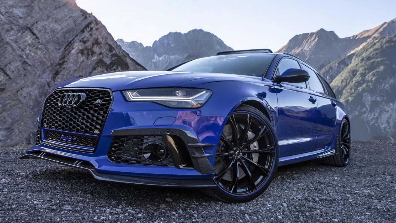 A blue Audi RS 6 Avant sits against a dramatic mountain backdrop