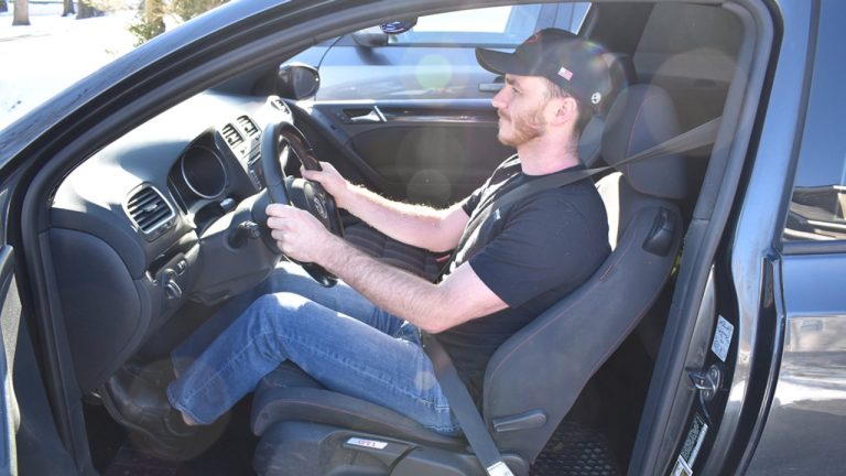A driver demonstrates a relaxed seating position while holding the steering wheel
