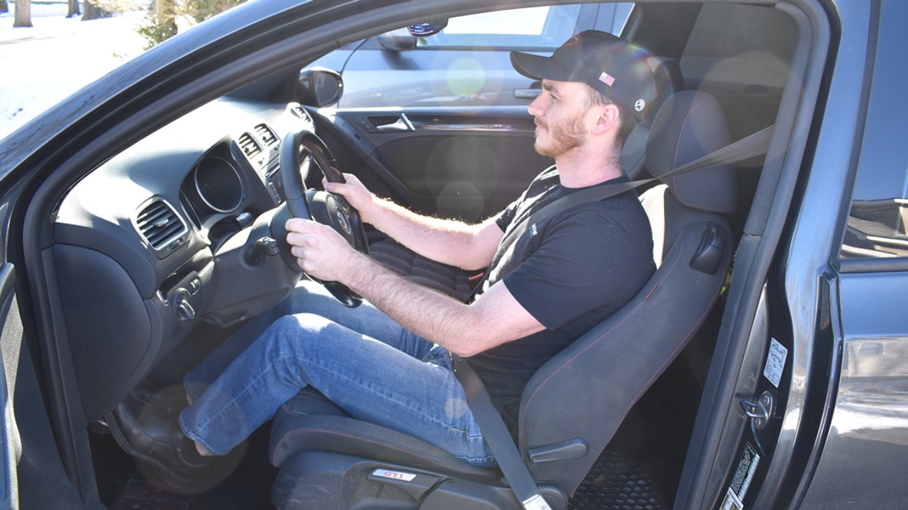 A driver demonstrates a relaxed seating position while holding the steering wheel