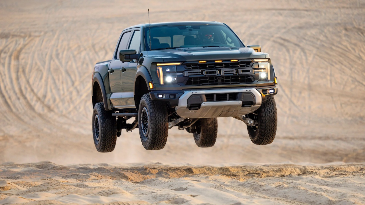 A Ford F-150 Raptor launches airborne over rugged desert terrain