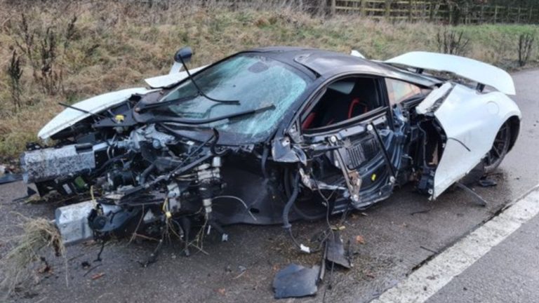 A heavily wrecked McLaren 720S rests roadside after a severe crash