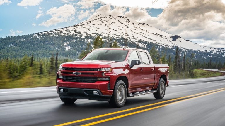A red Chevrolet Silverado Duramax drives along a scenic mountain highway