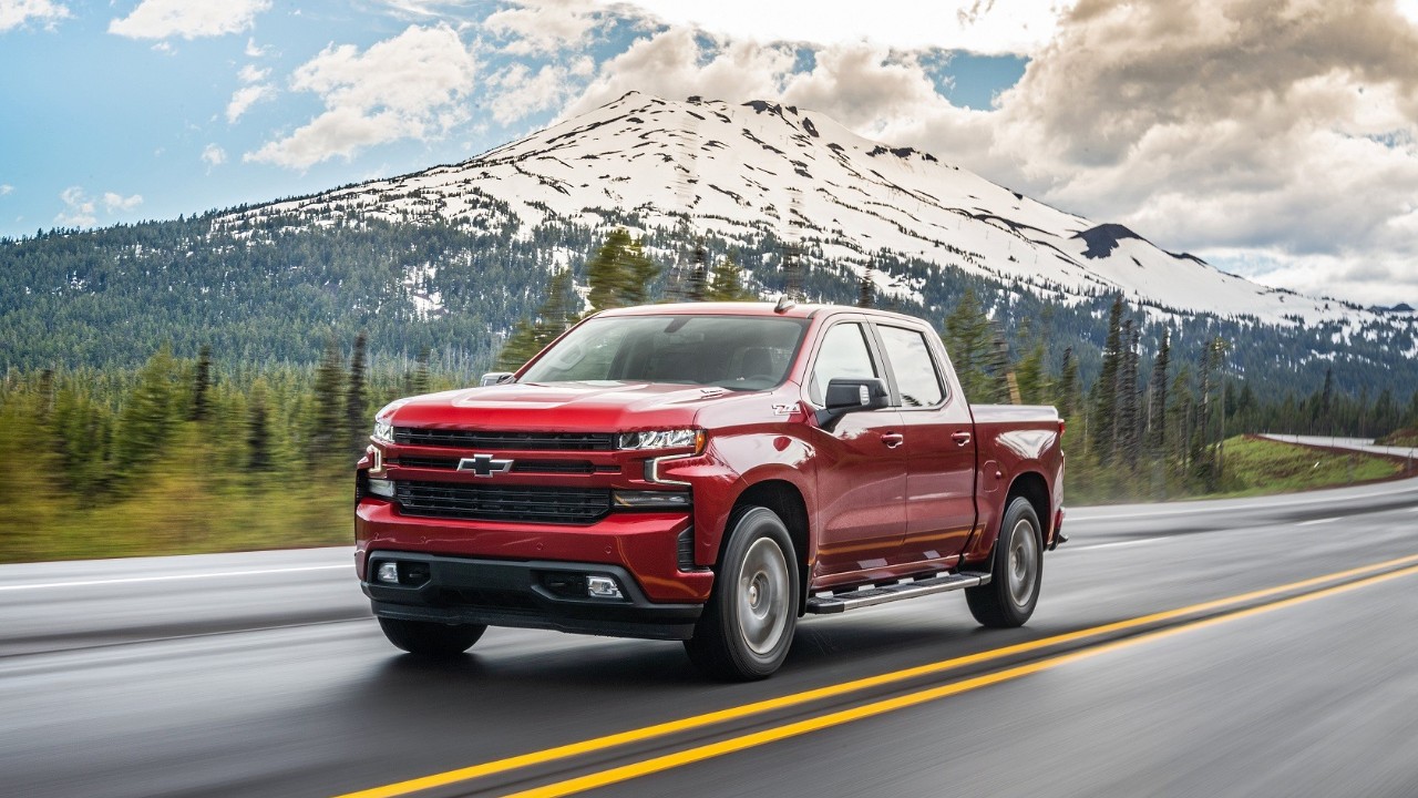 A red Chevrolet Silverado Duramax drives along a scenic mountain highway