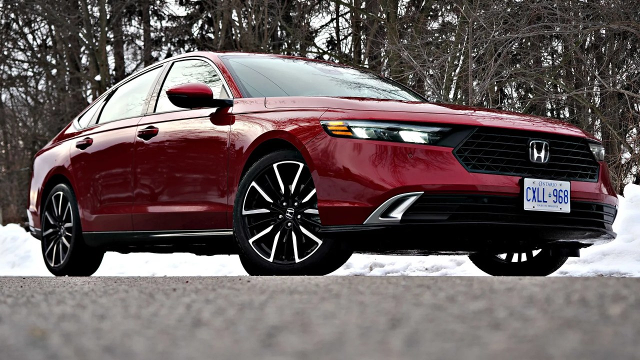 A red Honda Accord sits in snow, framed by a winter forest