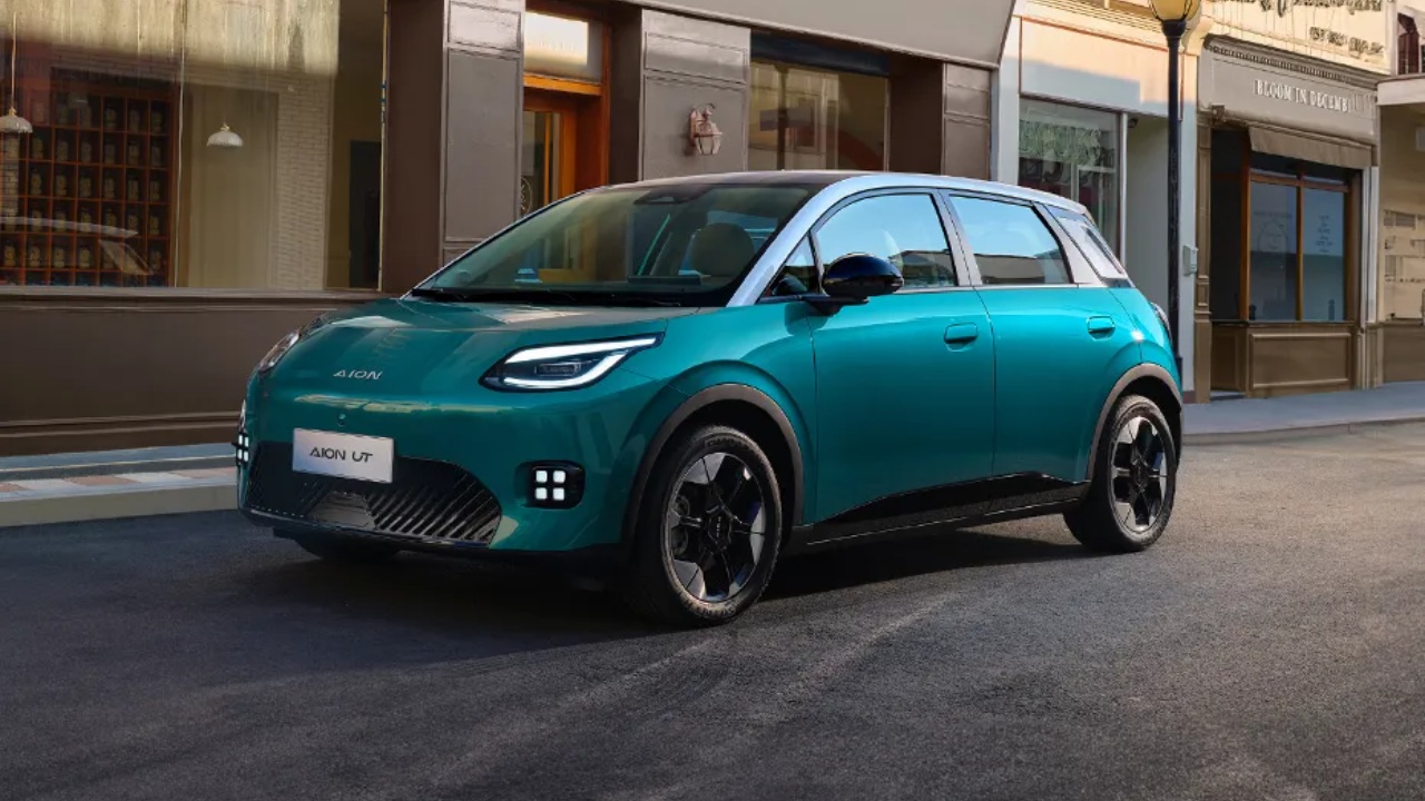 AION UT electric hatchback parked along a stylish urban street with storefronts