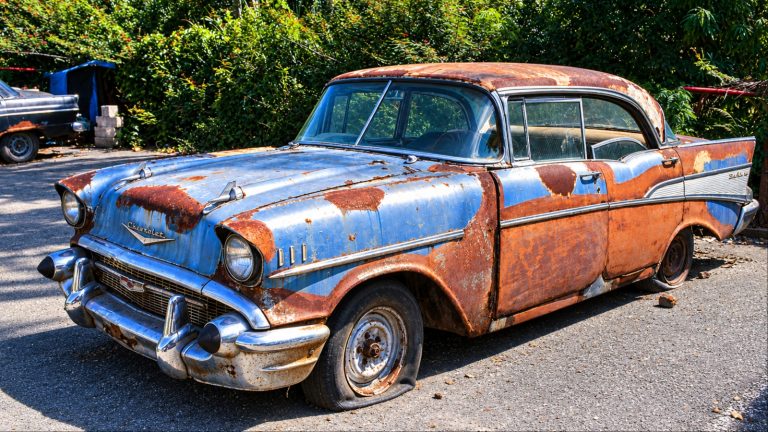 An old vintage car is standing in a bad condition