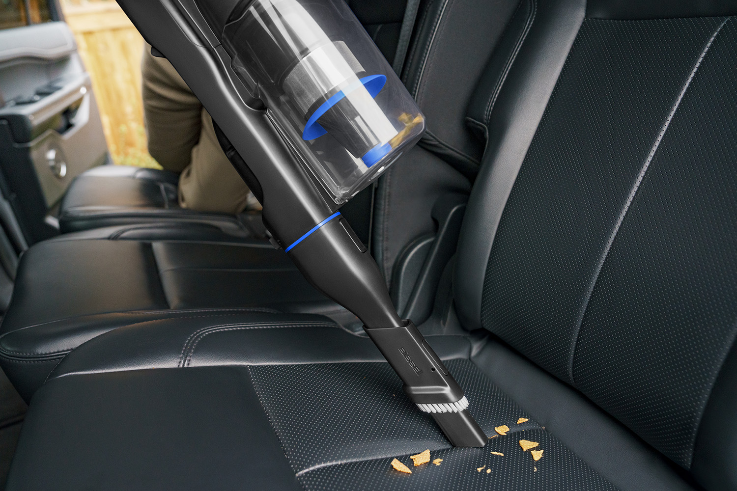 A man is trying ot clean his car with the help of a portable cleaner