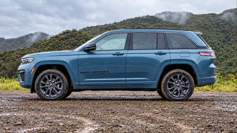 A Blue Jeep Grand Cherokee is standing on a muddy road