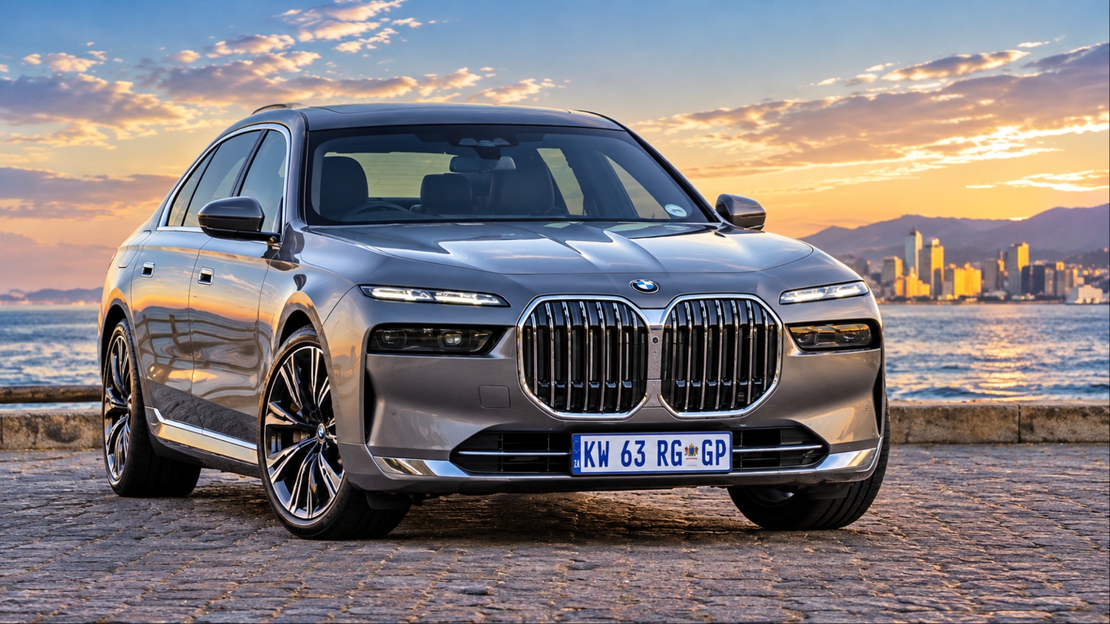 BMW i7 parked along a waterfront at sunset, showcasing its luxurious design and oversized kidney grille