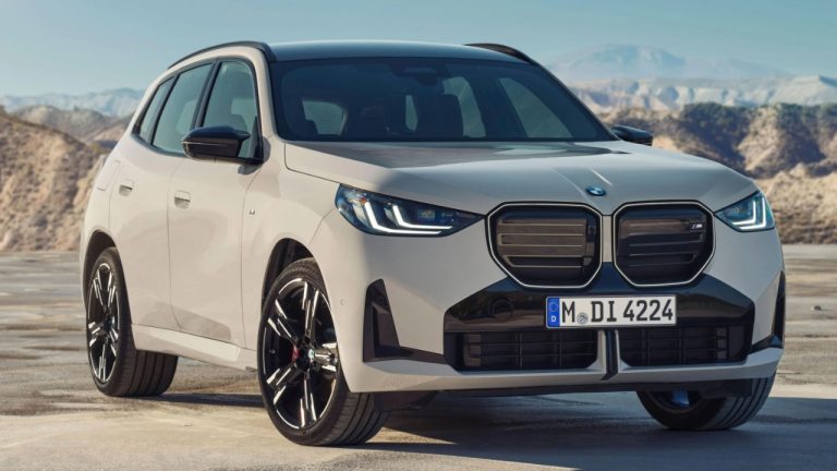 BMW X3 parked against a dramatic mountain landscape on a sunny day